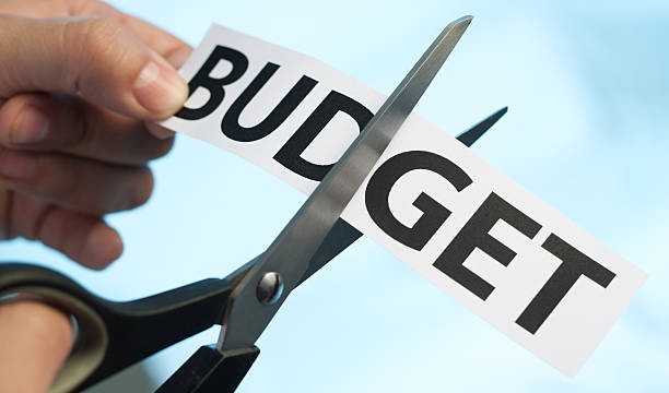 Scissors cutting the word "budget" on blue background